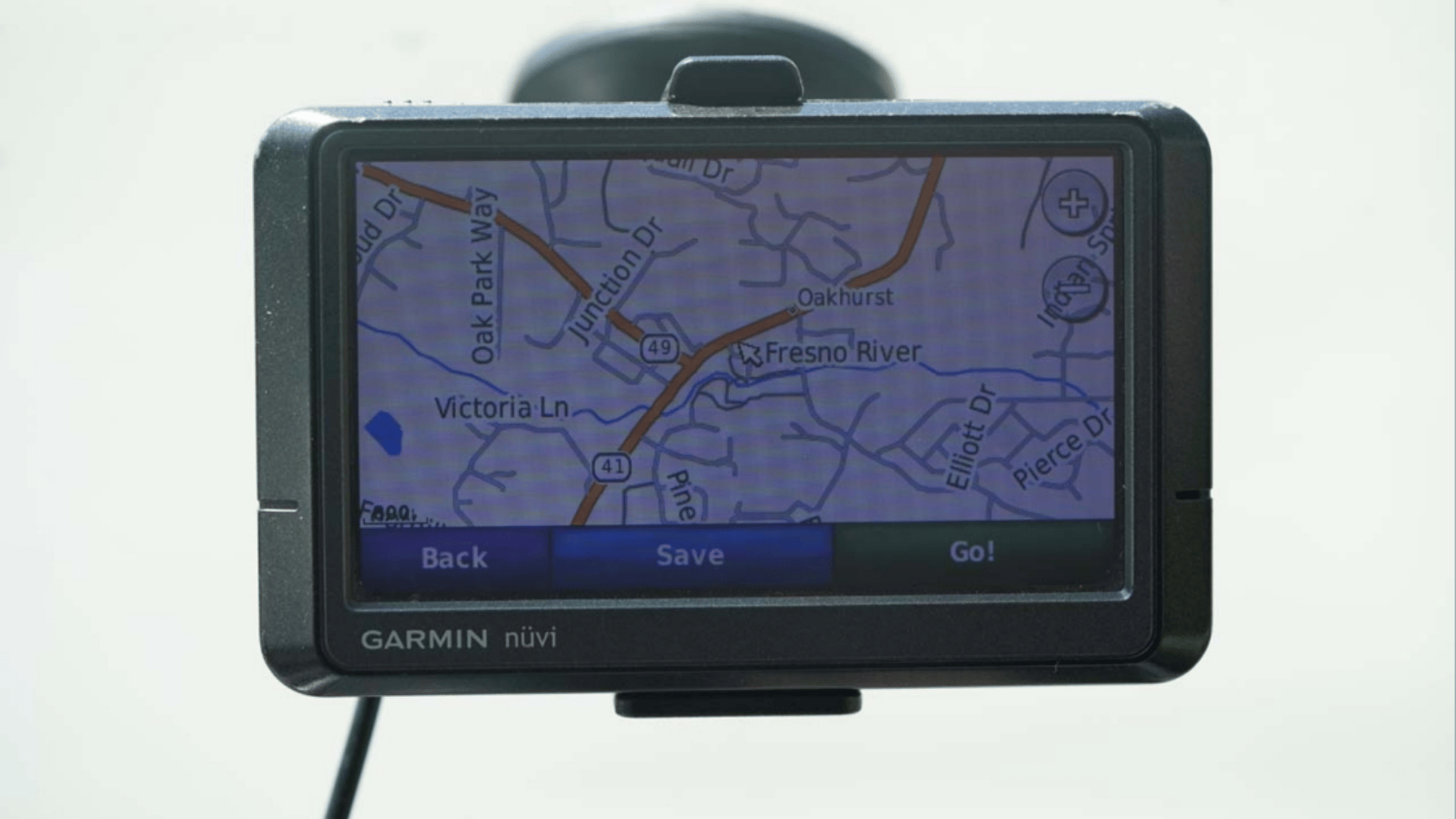 GPS navigation device mounted in a car showing a road map with streets and route options on screen.