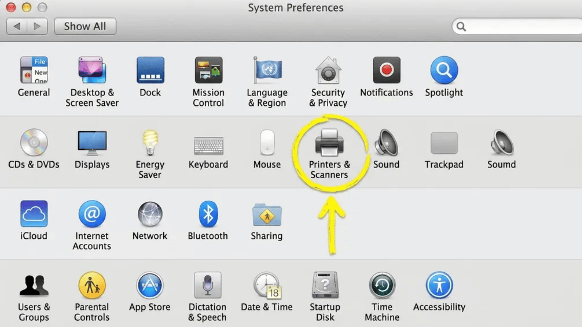 Mac System Preferences window showing icons grid with Printers & Scanners option circled in yellow and highlighted with an arrow pointing to it.