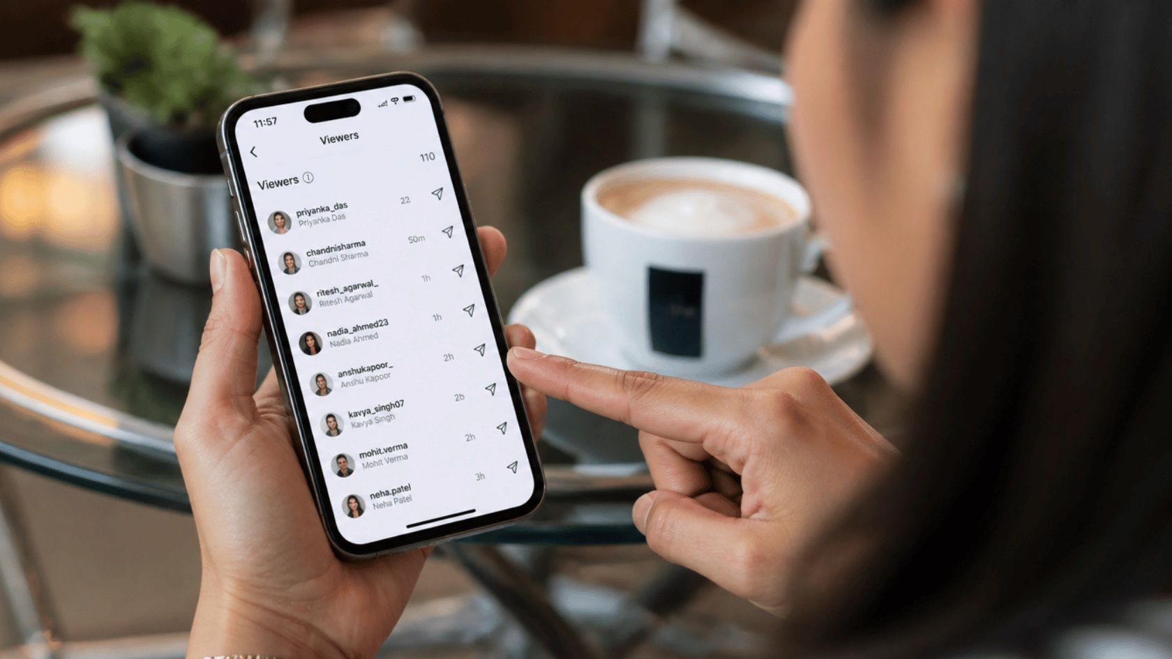 Man holding smartphone showing viewer list in social media insights, pointing at screen, coffee cup on table